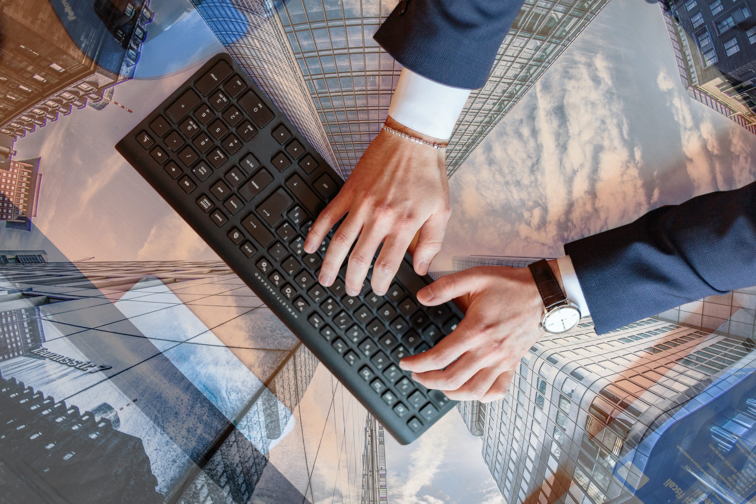 Man typing on a keyboard with city building overlayed on the desk